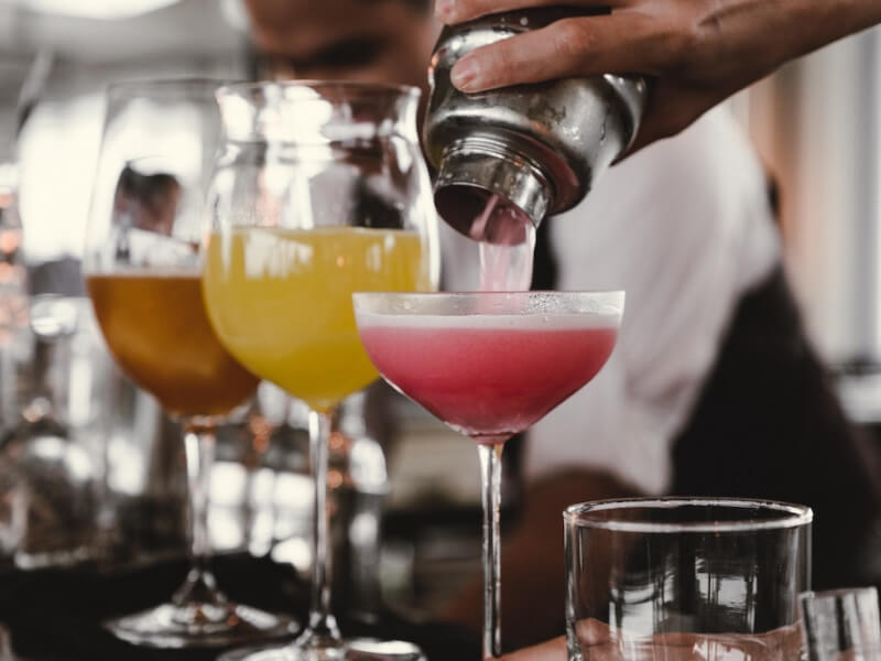 Three different coloured drinks in round shaped glasses on a cocktail bar